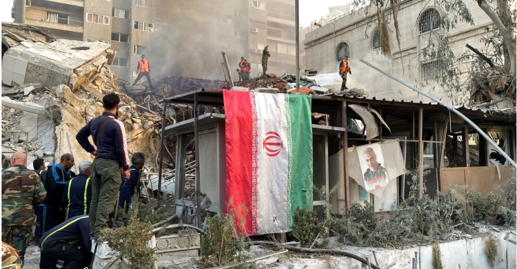 Seorang petugas keamanan Kedutaan Besar Iran di Damaskus, Suriah, memantau proses evakuasi puing gedung Konsulat Iran yang diserang Israel, Senin (1/4/2024) petang. MAKDESI/ REUTERS